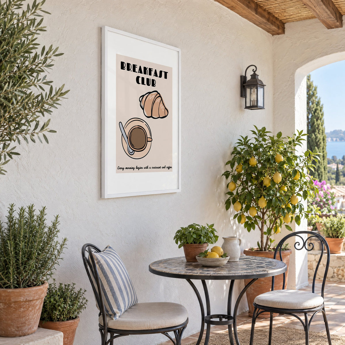 Breakfast Club croissant and coffee print in a white frame on a sunny patio wall beside a potted lemon tree