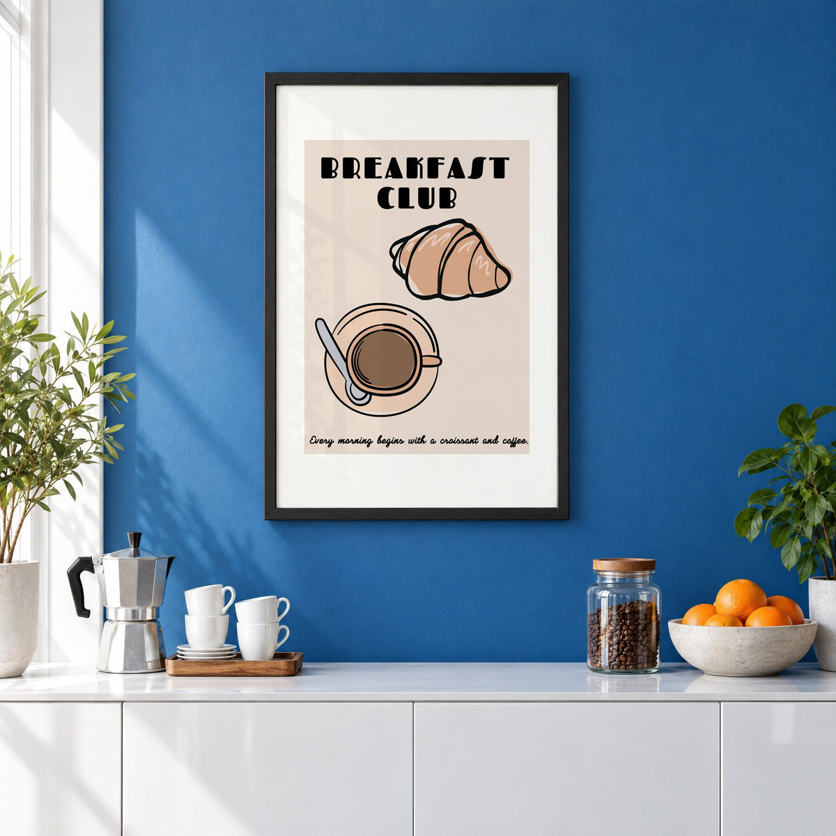Breakfast Club croissant and coffee print in a black frame on a cobalt blue wall above a coffee station