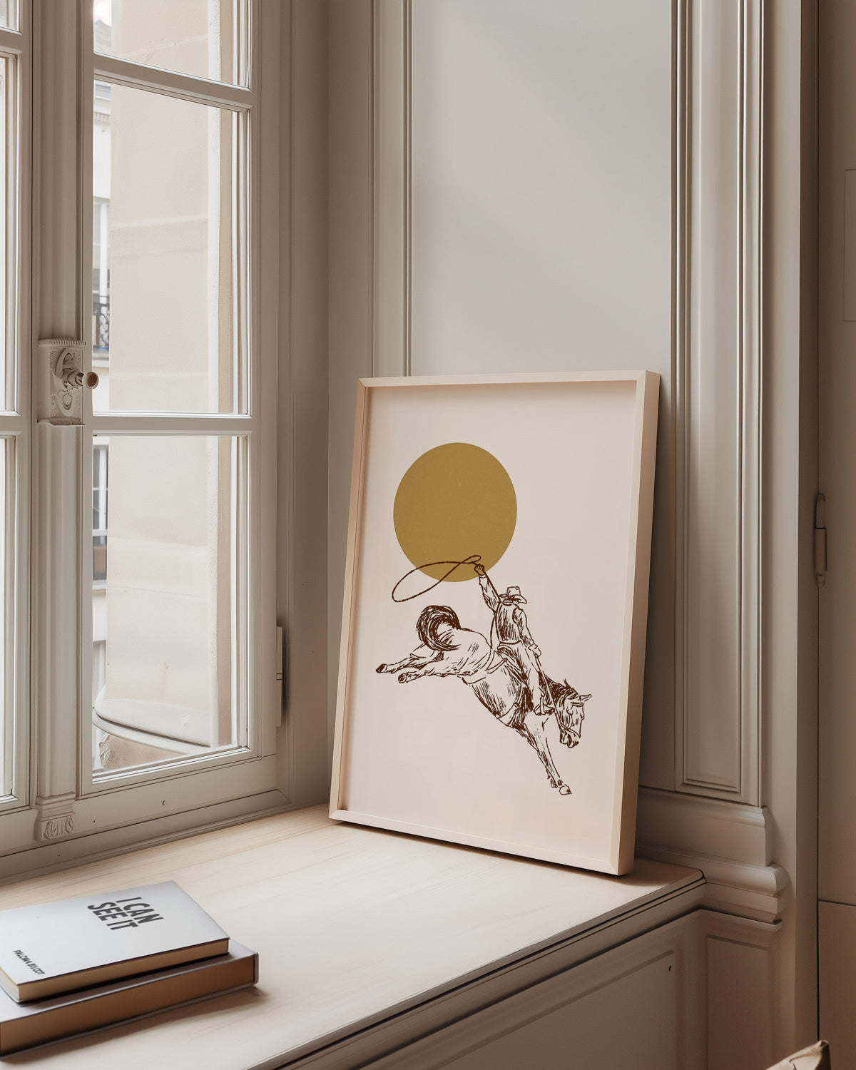 Bronco rider golden sun print in a pale wood frame on a sunlit window ledge