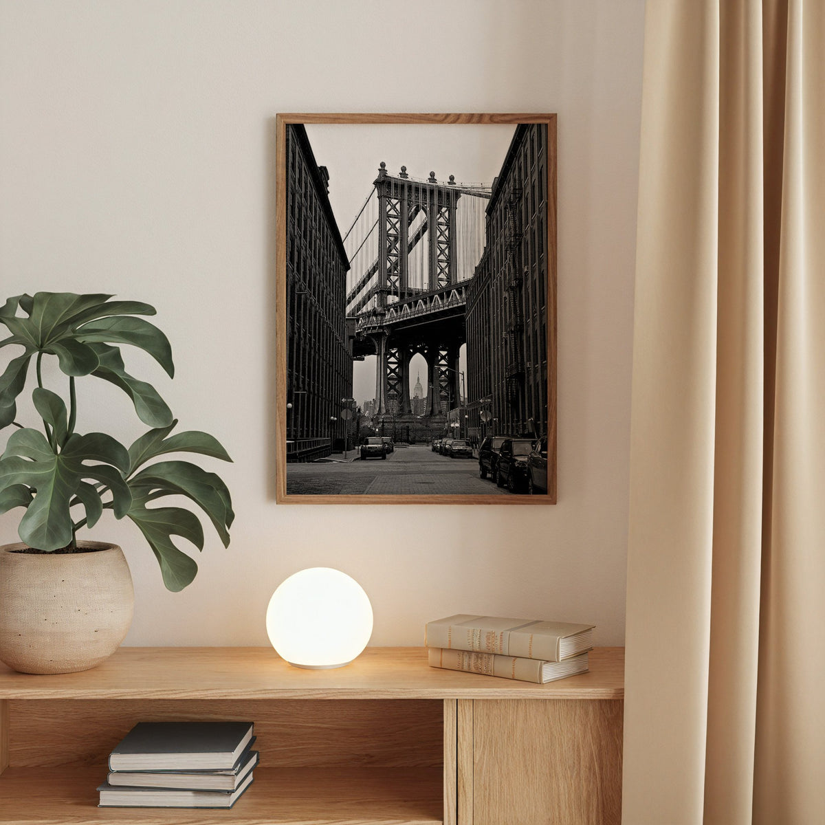 Manhattan Bridge between brick buildings print in a walnut frame above an oak cabinet with a glowing globe lamp