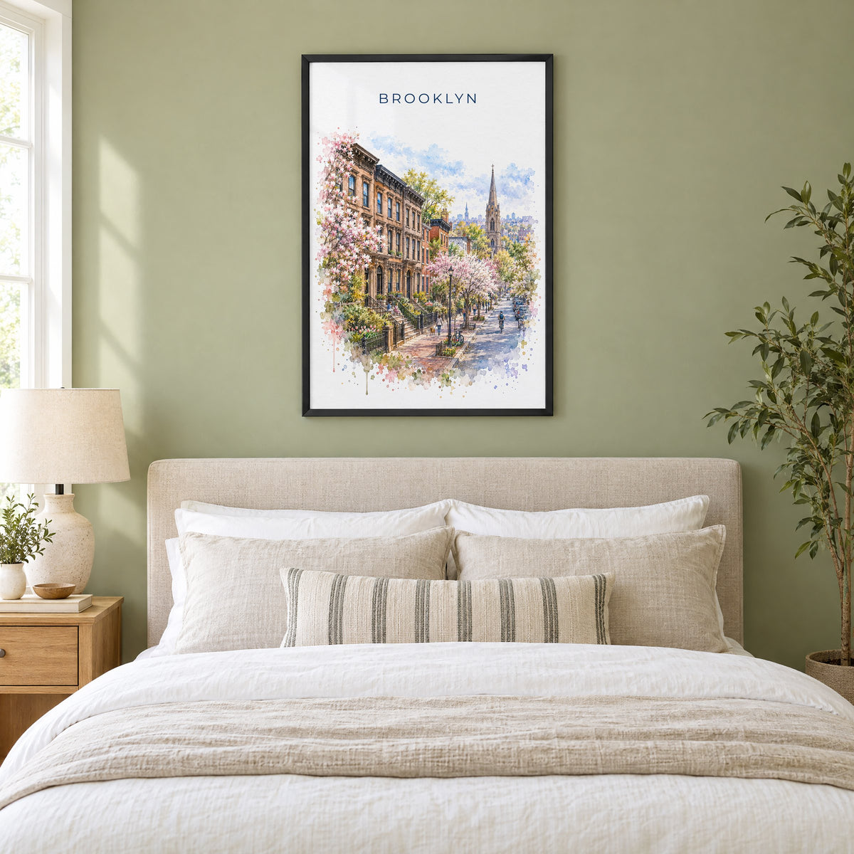 Brooklyn watercolor print in a black frame above an upholstered headboard in a sage green bedroom