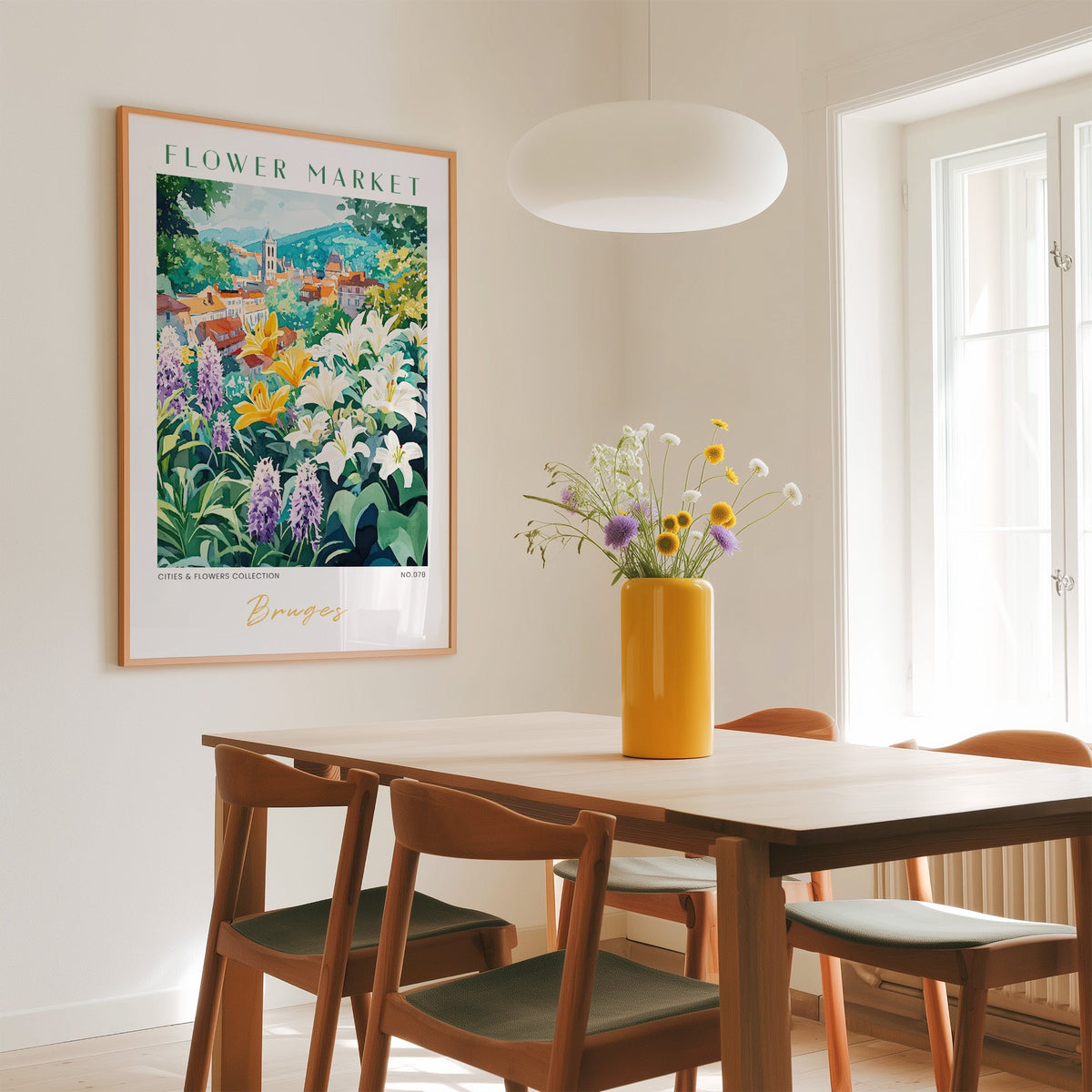 Bruges flower market print in an oak frame above a dining table with a yellow vase and white pendant light