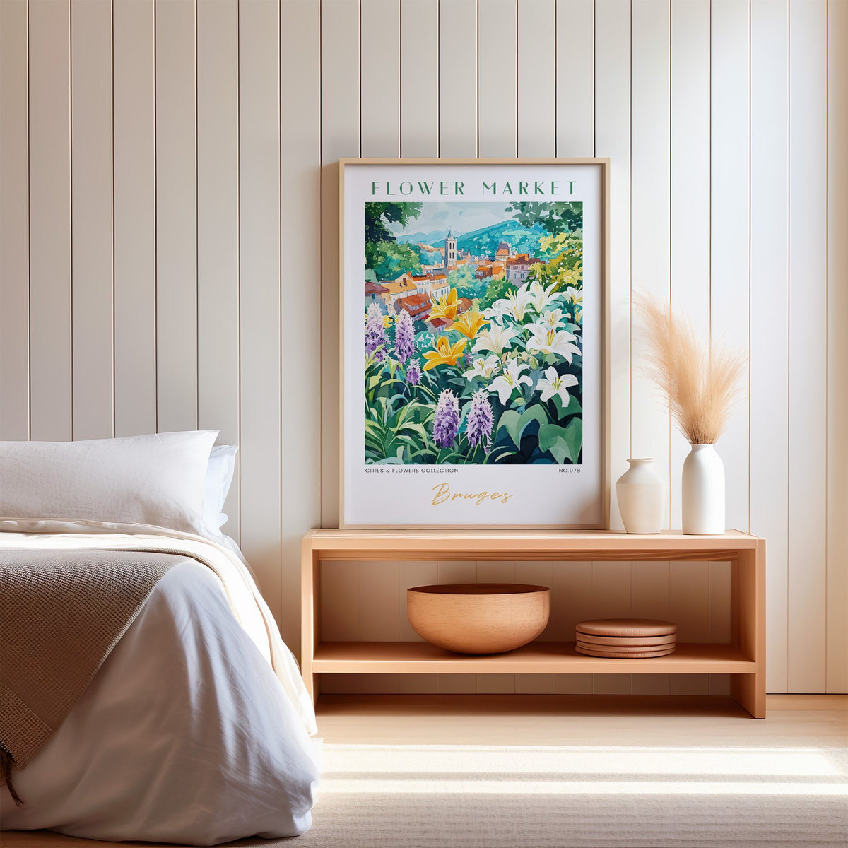 Bruges flower market print in an oak frame on a wood bench against a white shiplap bedroom wall with pampas grass