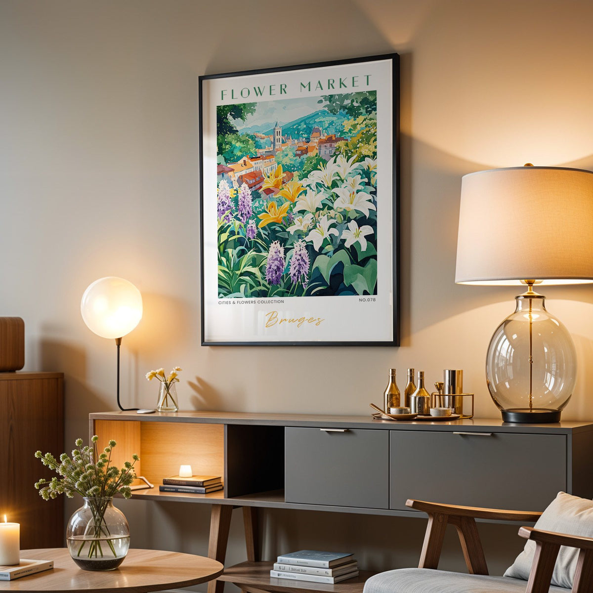 Bruges flower market print in a black frame above a grey media console with a glass table lamp