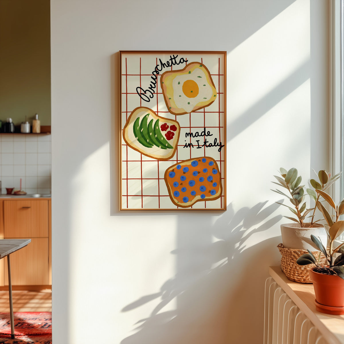 Bruschetta print in a gold frame in sunlight with plants on the ledge and a kitchen beyond