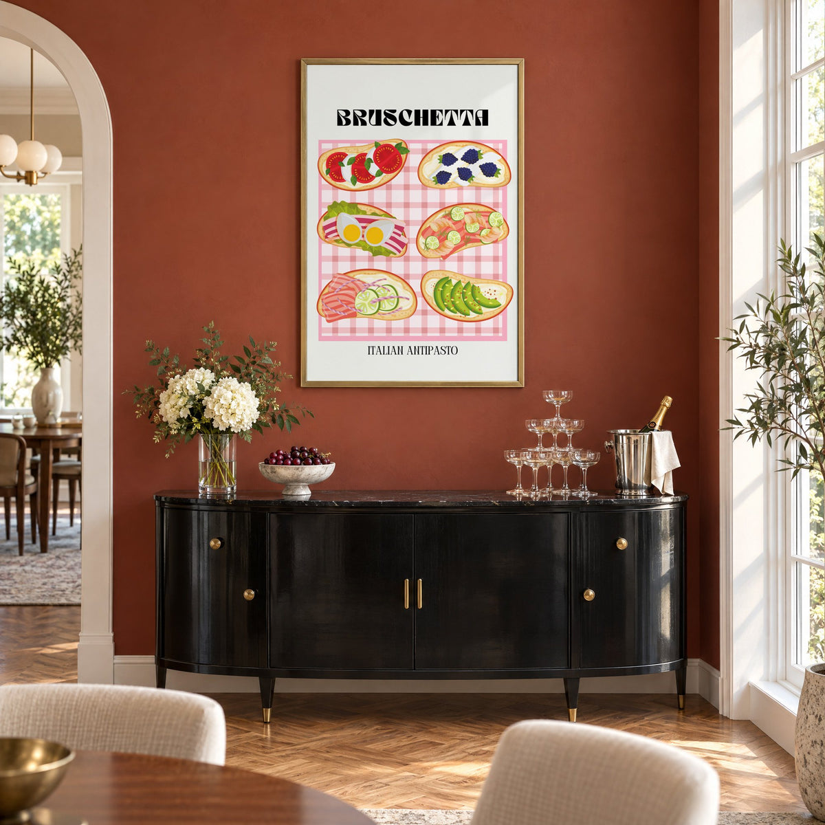 BRUSCHETTA pink gingham print in a brass frame on a terracotta wall above a black buffet with a champagne tower