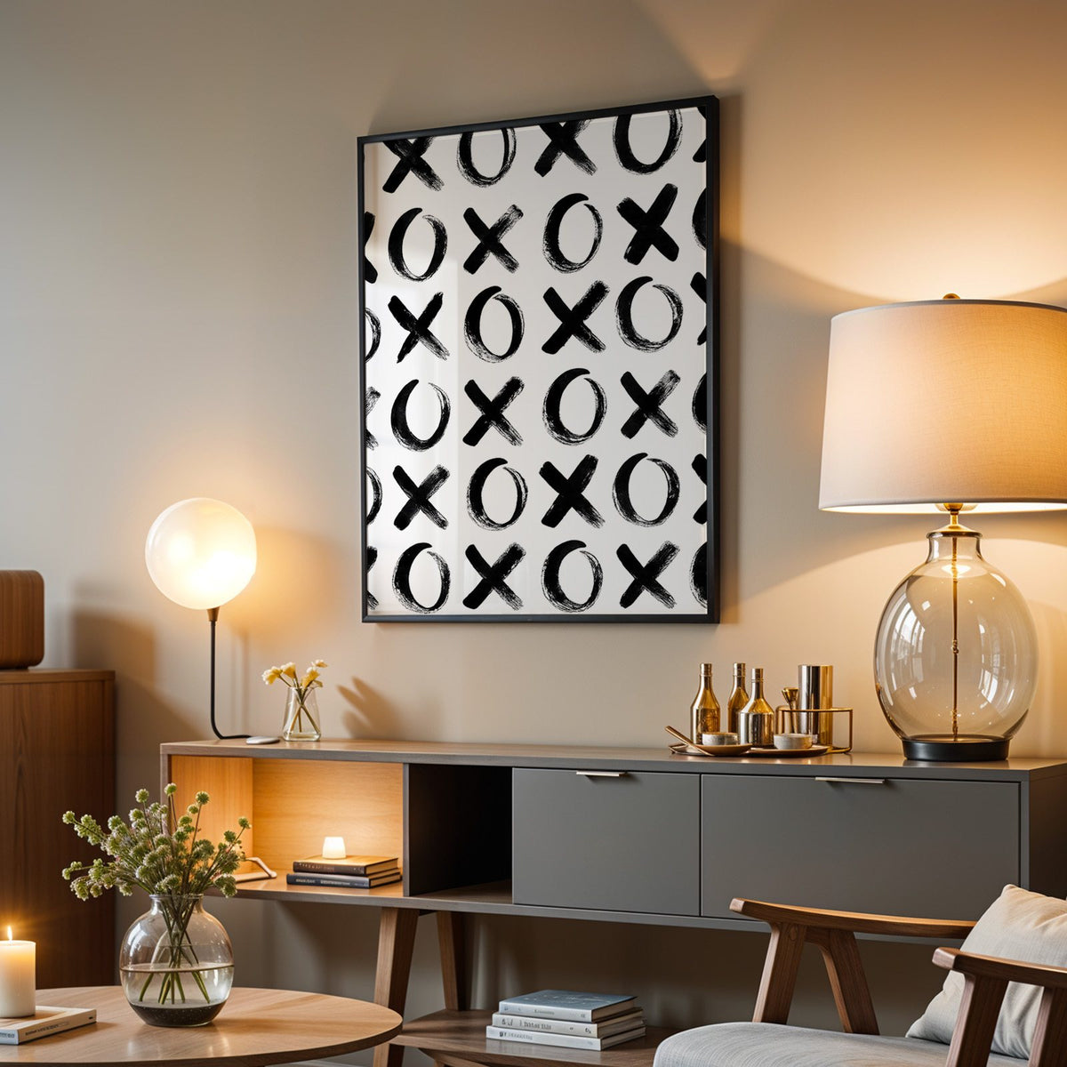 Hand-brushed XOXO pattern print in a black frame above a grey media console with a glass table lamp