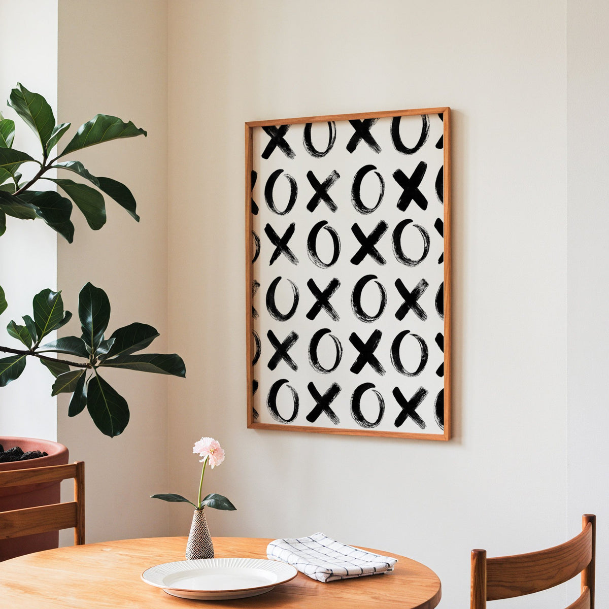 Hand-brushed XOXO pattern print in a teak frame above a round wooden dining table