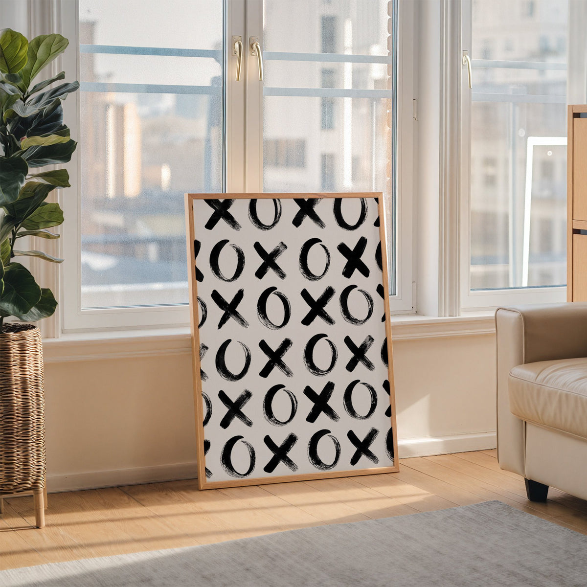Hand-brushed XOXO pattern print in an oak frame leaning on the floor beside a fiddle leaf fig