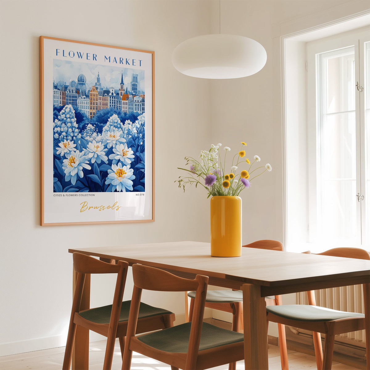 Brussels flower market print in an oak frame above a dining table with a yellow vase and white pendant light