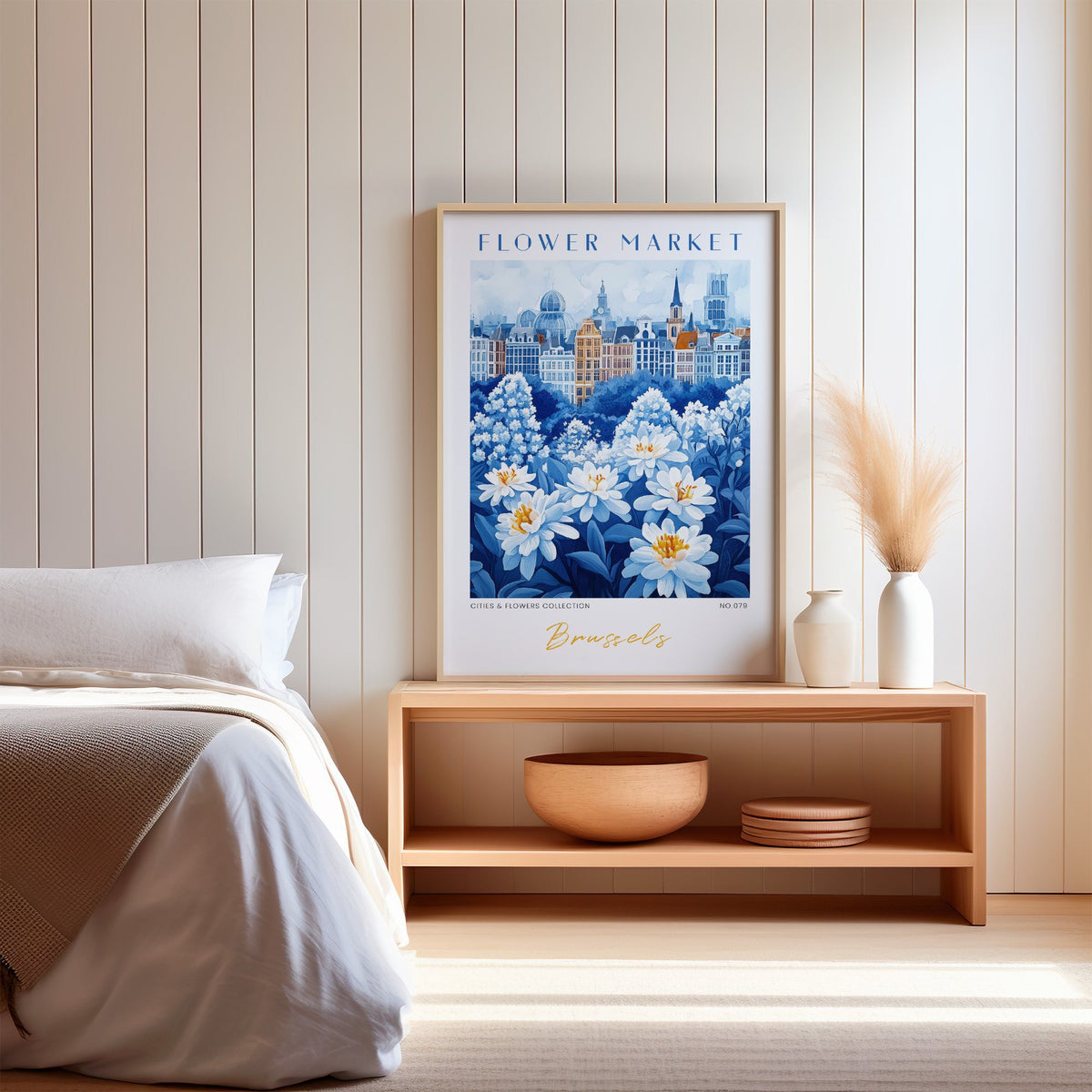 Brussels flower market print in an oak frame on a wood bench against a white shiplap bedroom wall with pampas grass