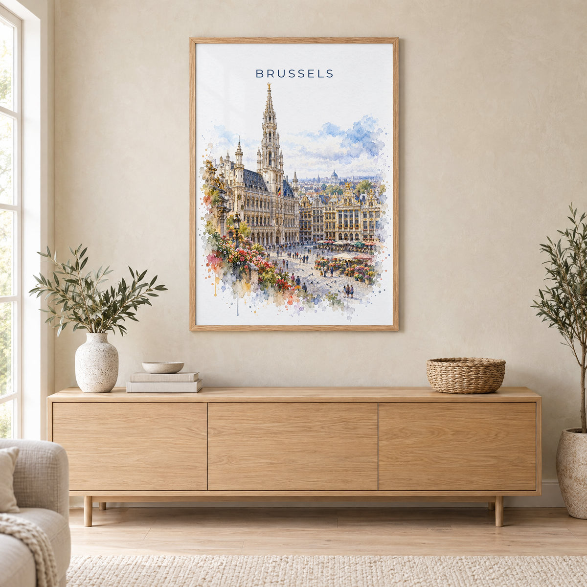 Brussels watercolor print in an oak frame above a light wood sideboard in a Scandinavian living room