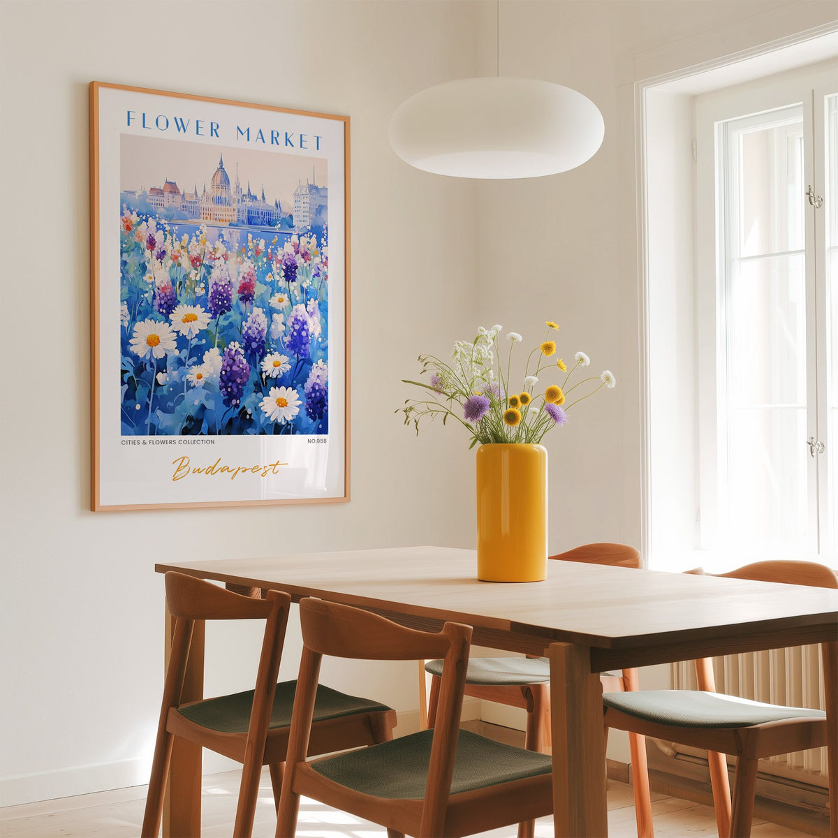 Budapest flower market print in an oak frame above a dining table with a yellow vase and white pendant light