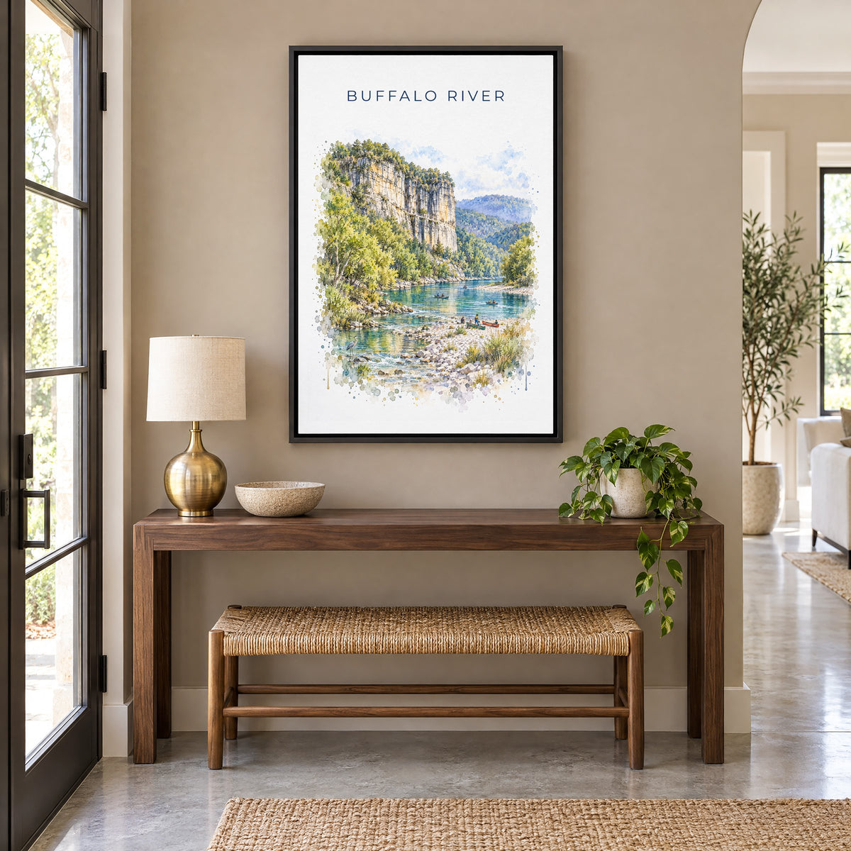 Buffalo National River watercolor print as a black floater canvas above a walnut console and woven bench in an entryway