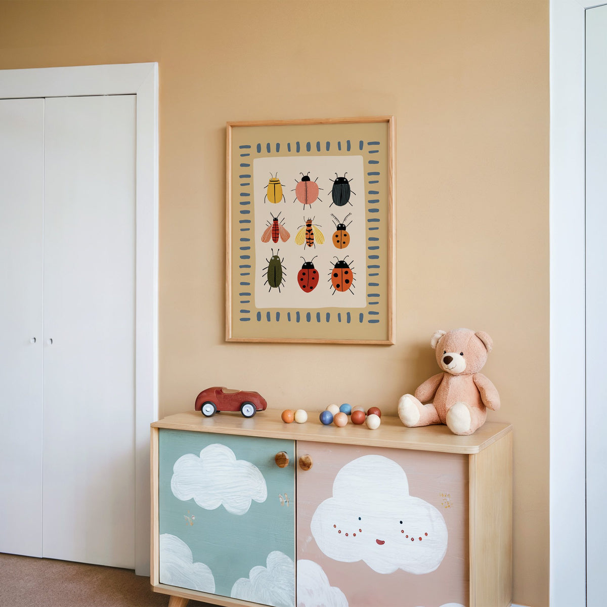Bug collection chart nursery print in an oak frame on a peach wall above a cloud-painted cabinet