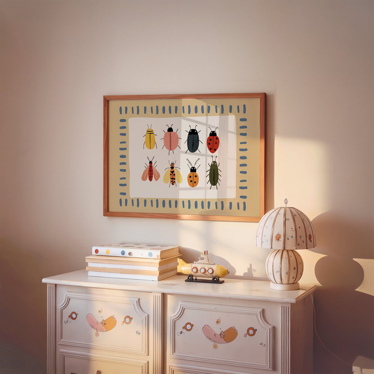 Landscape bug collection chart nursery print in a cherry wood frame above a painted dresser and lamp