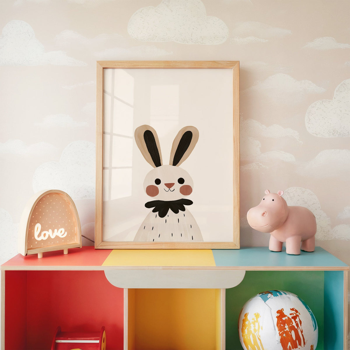 Bunny black ruffle collar nursery print in an oak frame on a rainbow toy shelf against cloud wallpaper