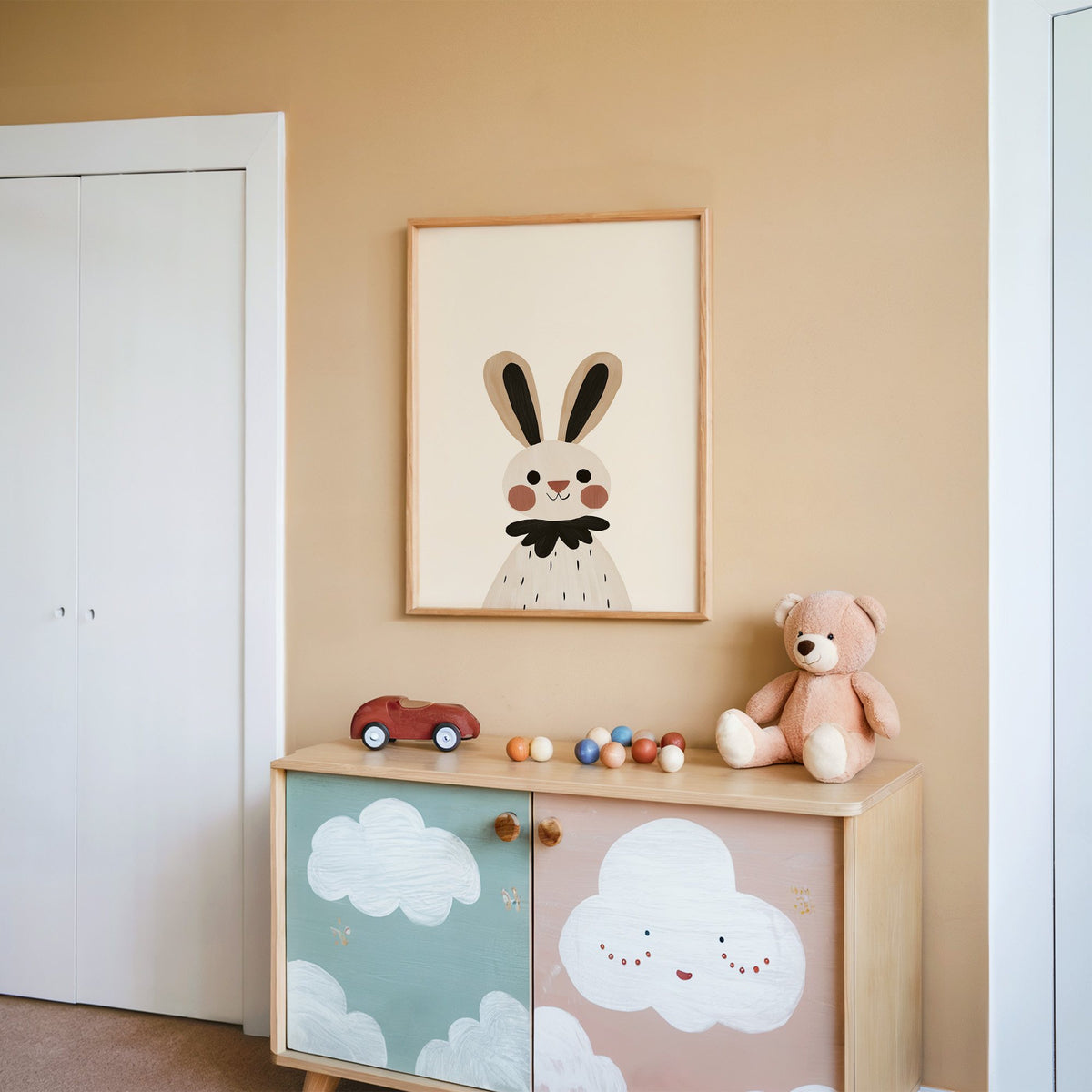 Bunny black ruffle collar nursery print in an oak frame on a peach wall above a cloud-painted cabinet