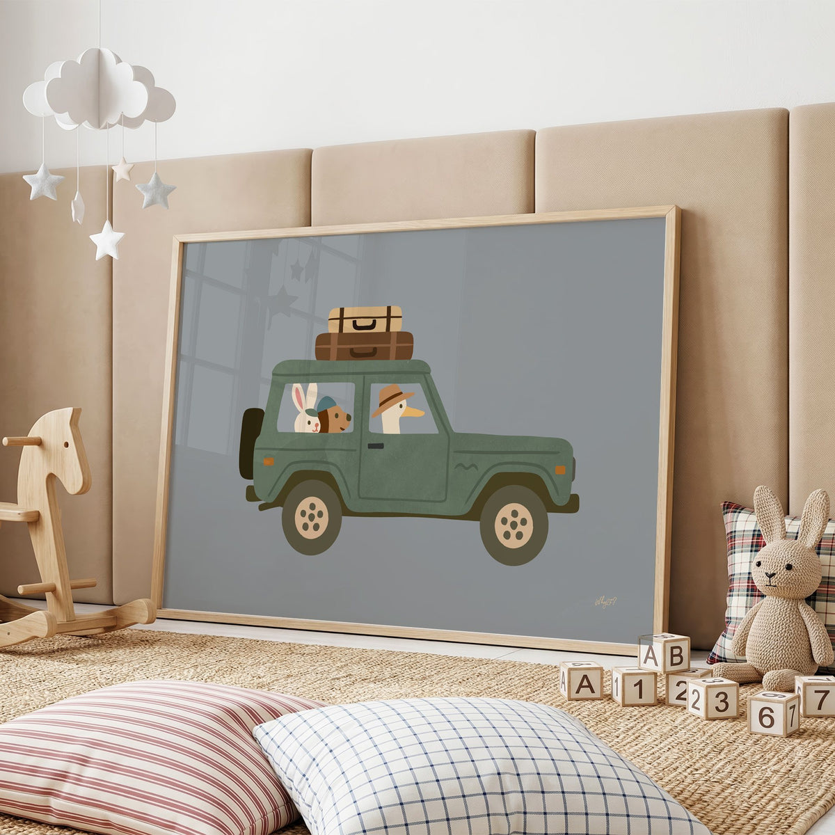 Animals riding green vintage suv nursery print in an oak frame on a padded wall by a wooden rocking horse