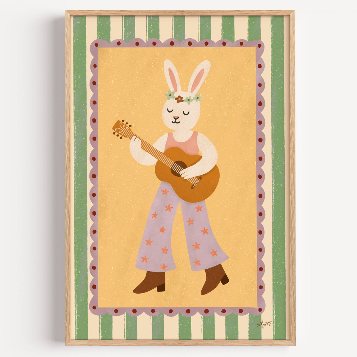 Bunny playing guitar with flower crown nursery print in a light oak frame on a plain white wall
