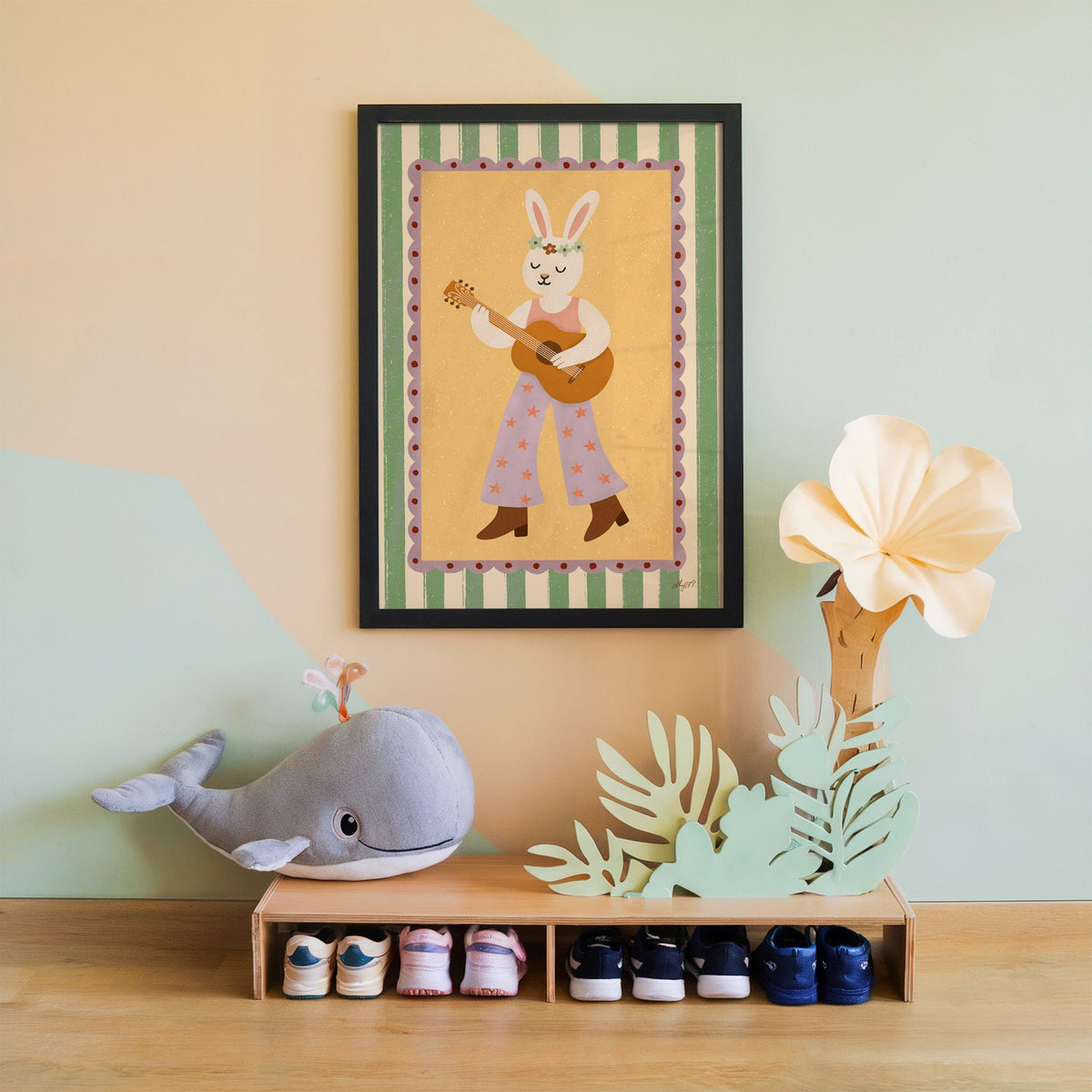 Bunny playing guitar with flower crown nursery print in a black frame on a mint and peach wall above a whale plush
