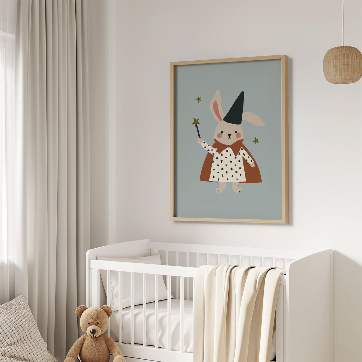 Bunny magician star wand nursery print in an oak frame above a white crib with a teddy bear