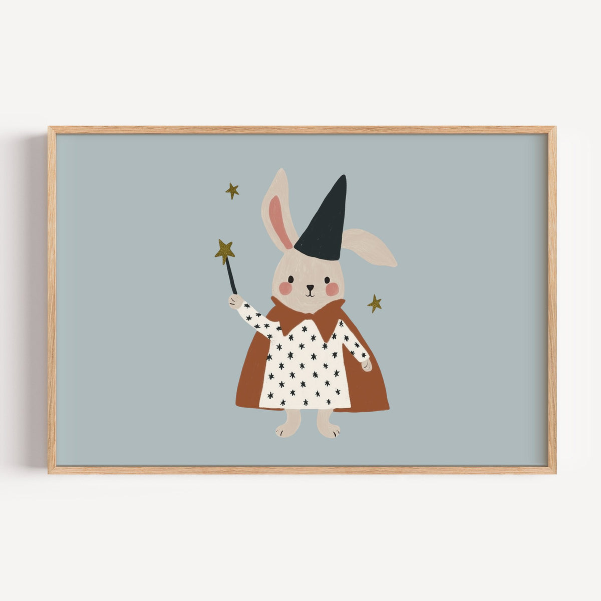 Landscape bunny magician star wand nursery print in a light oak frame on a plain white wall