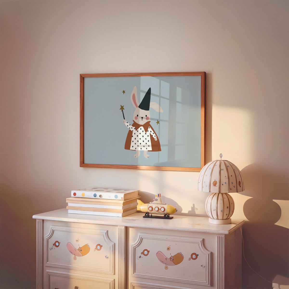 Landscape bunny magician star wand nursery print in a cherry wood frame above a painted dresser and lamp