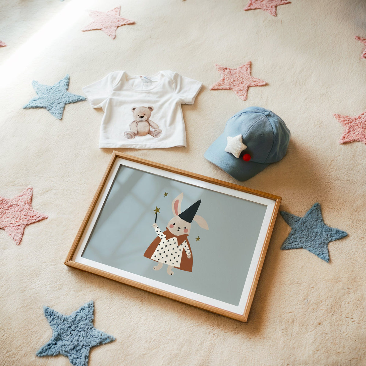 Landscape bunny magician star wand nursery print in a matted oak frame on a star rug with a baby tee