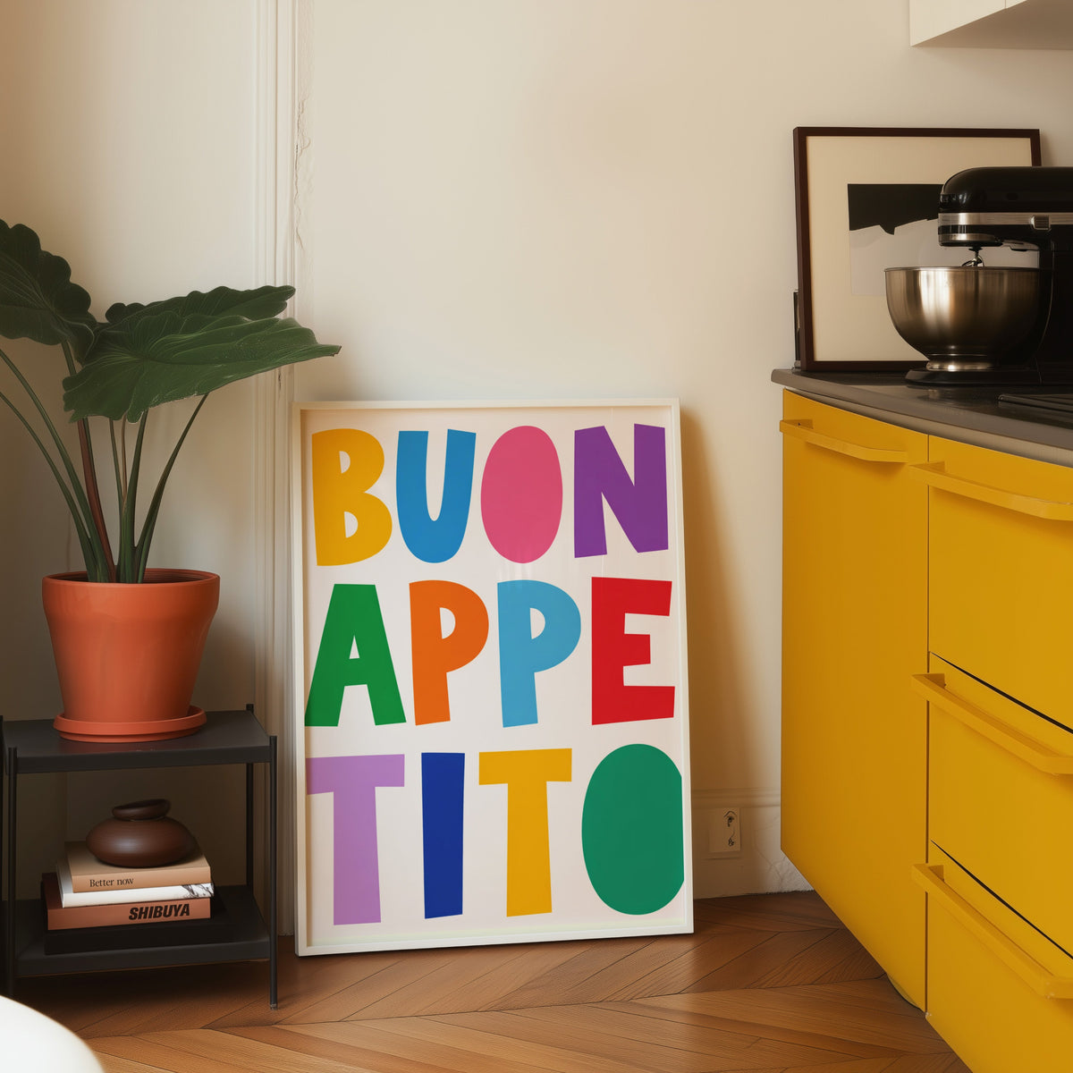 Buon Appetito print in a white frame leaning on parquet beside a bright yellow kitchen