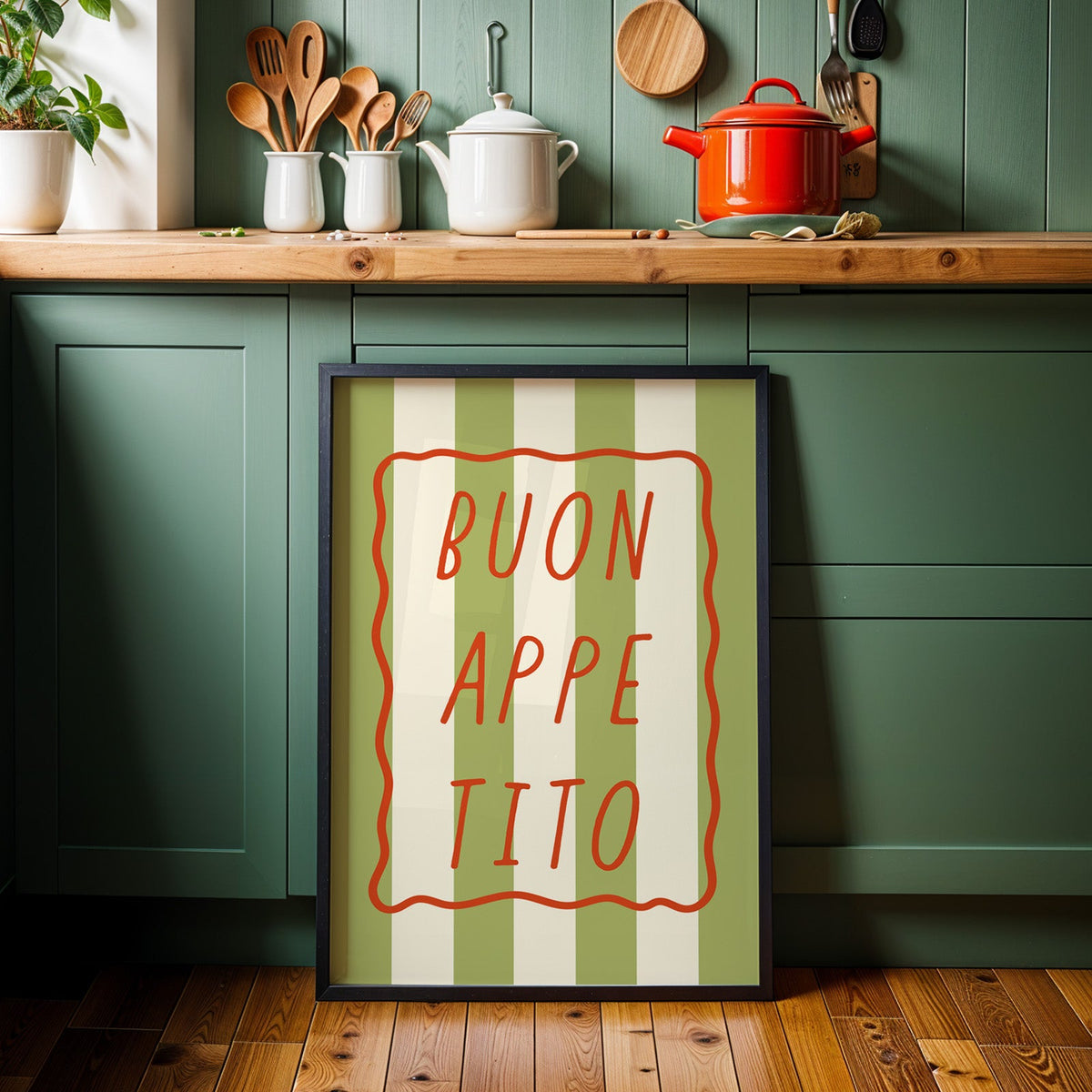 Buon appetito print in a black frame against sage green kitchen cabinets