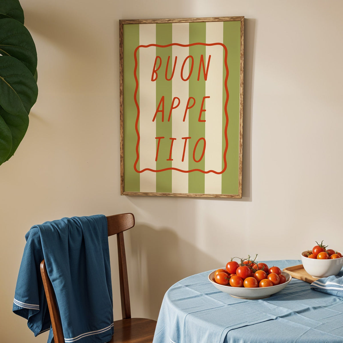 Buon appetito print in an oak frame above a blue linen table with ripe tomatoes