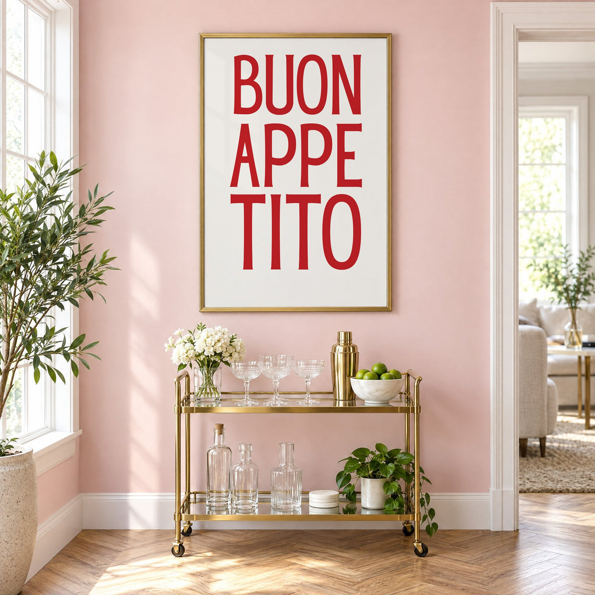 BUON APPE TITO red condensed type print in a brass frame on a blush pink wall above a gold bar cart with glassware
