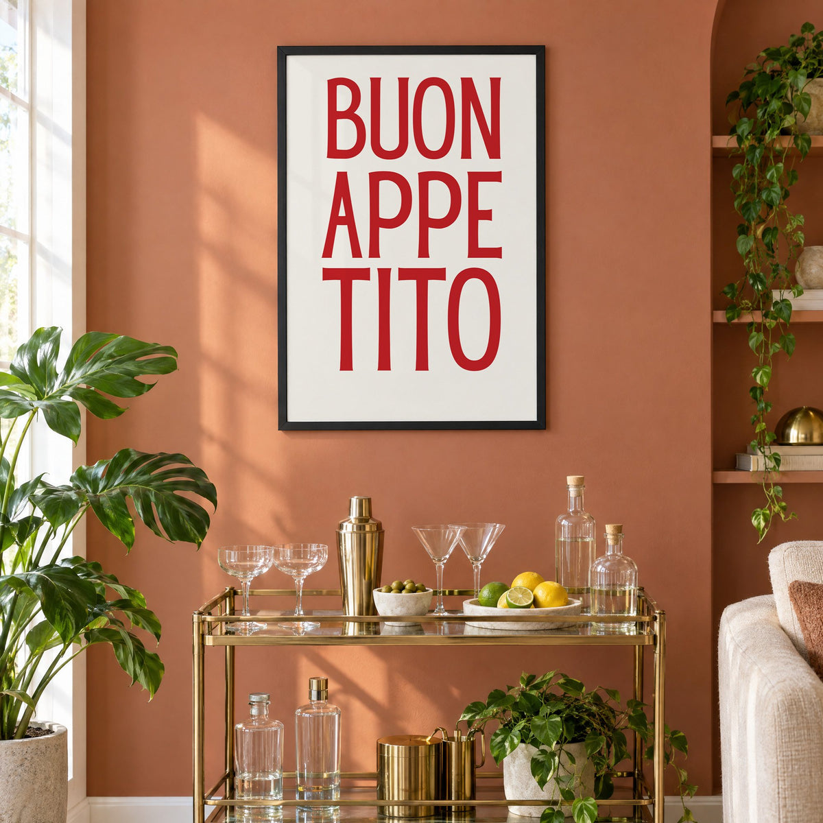 BUON APPE TITO red condensed type print in a black frame on a terracotta wall above a brass bar cart with coupes and citrus