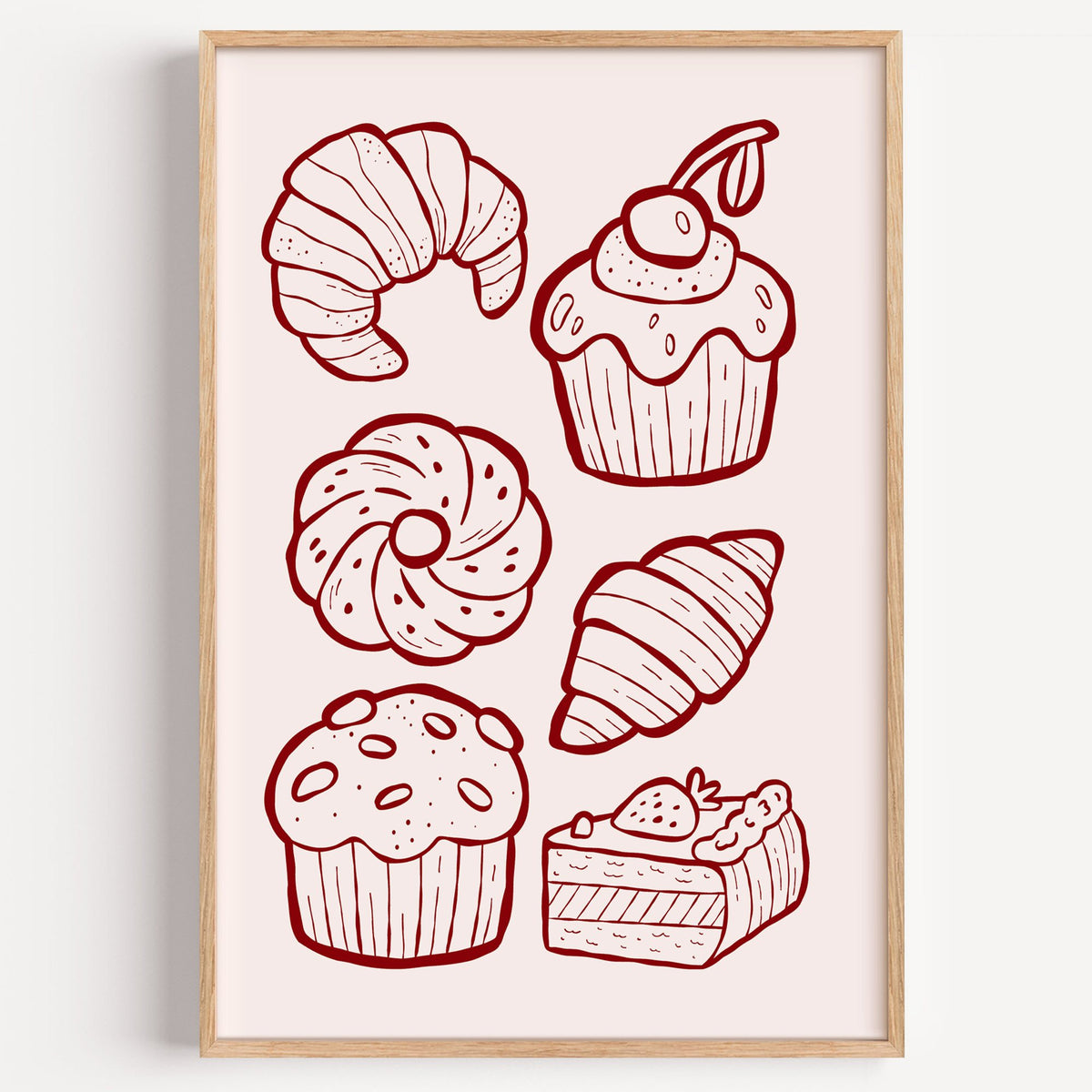 Burgundy line croissants and cupcake pastries print in a light oak frame on a plain white wall