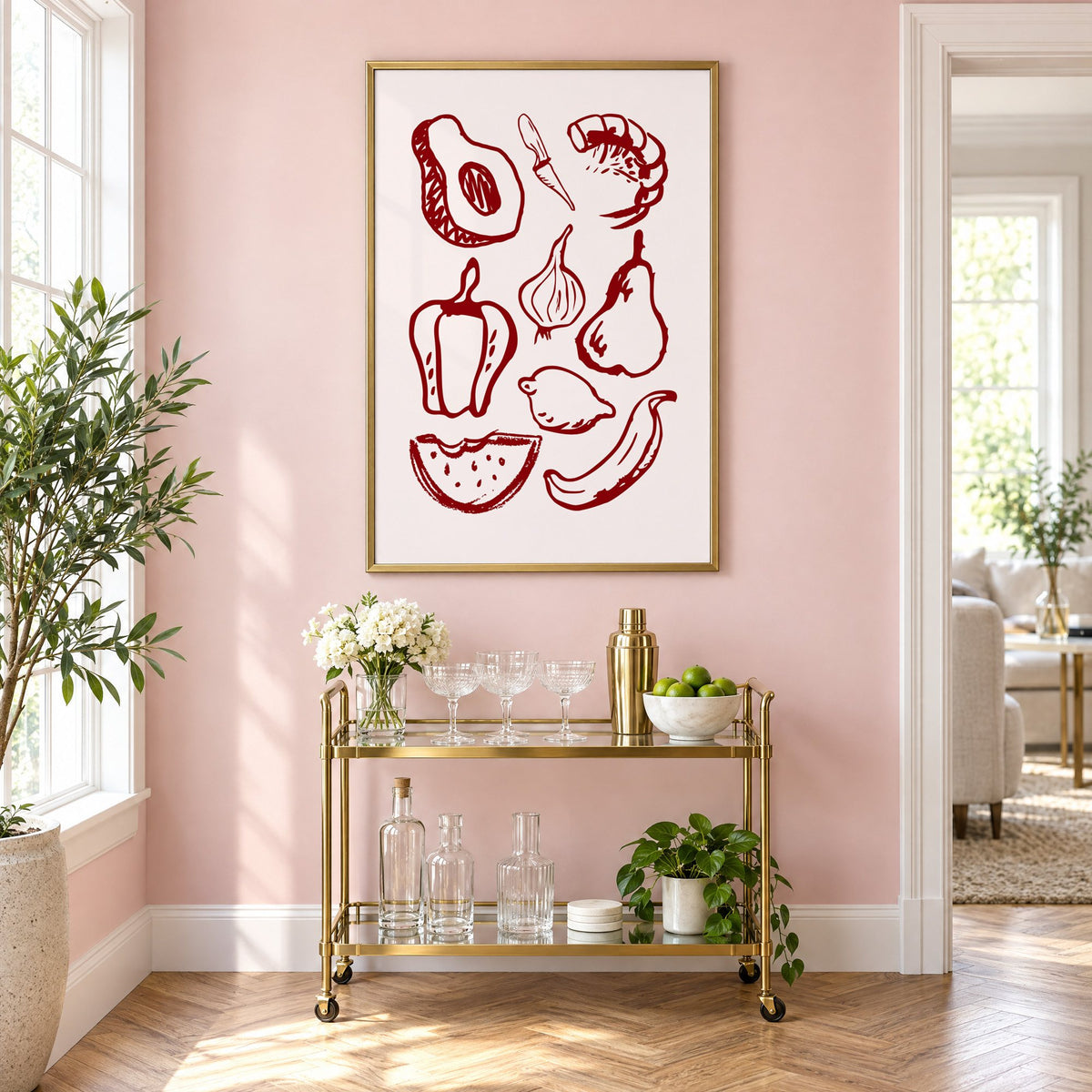 Burgundy line vegetables and fruit sketch print in a brass frame on a blush pink wall above a gold bar cart with glassware
