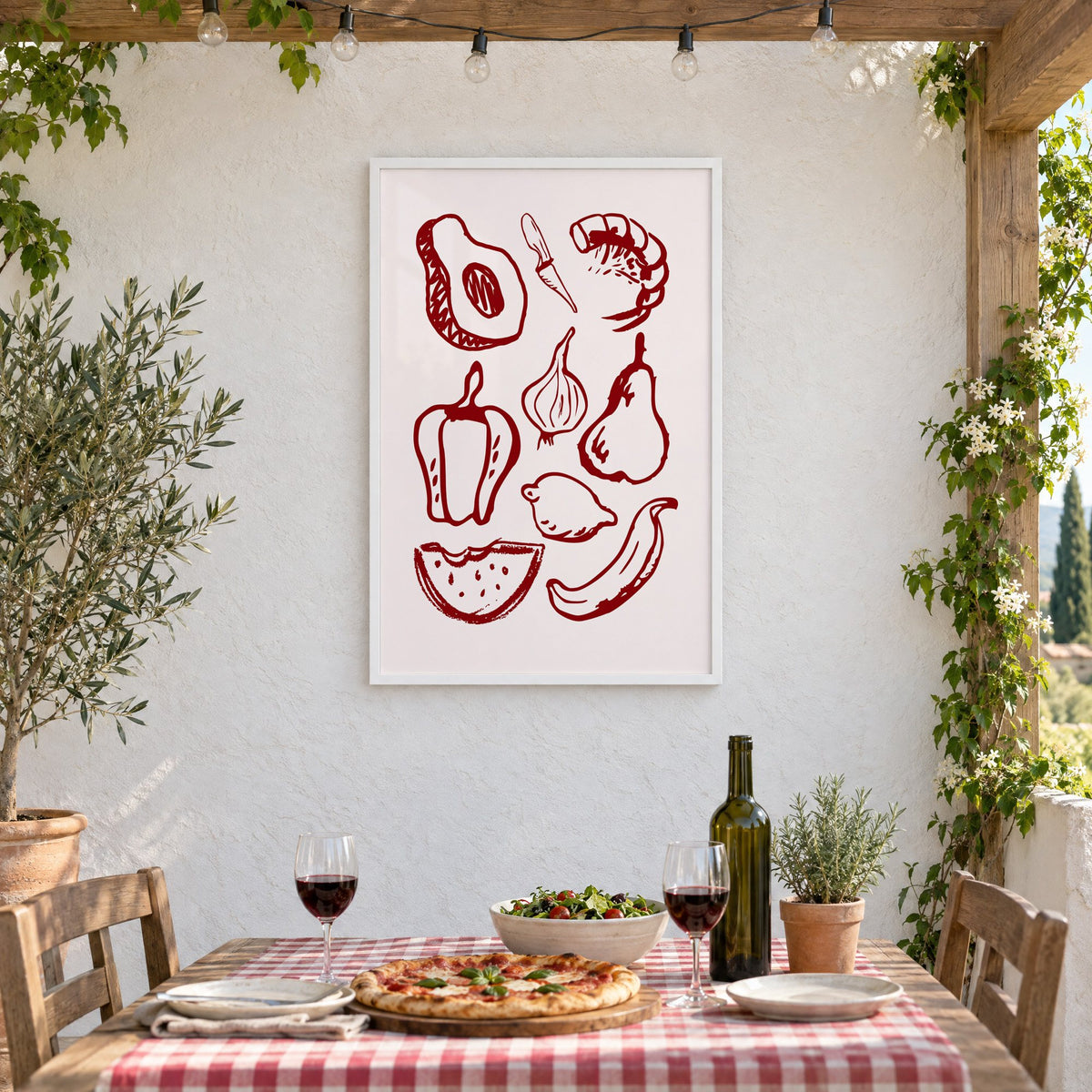 Burgundy line vegetables and fruit sketch print in a white frame on a stucco wall above a checked-cloth table with pizza and red wine
