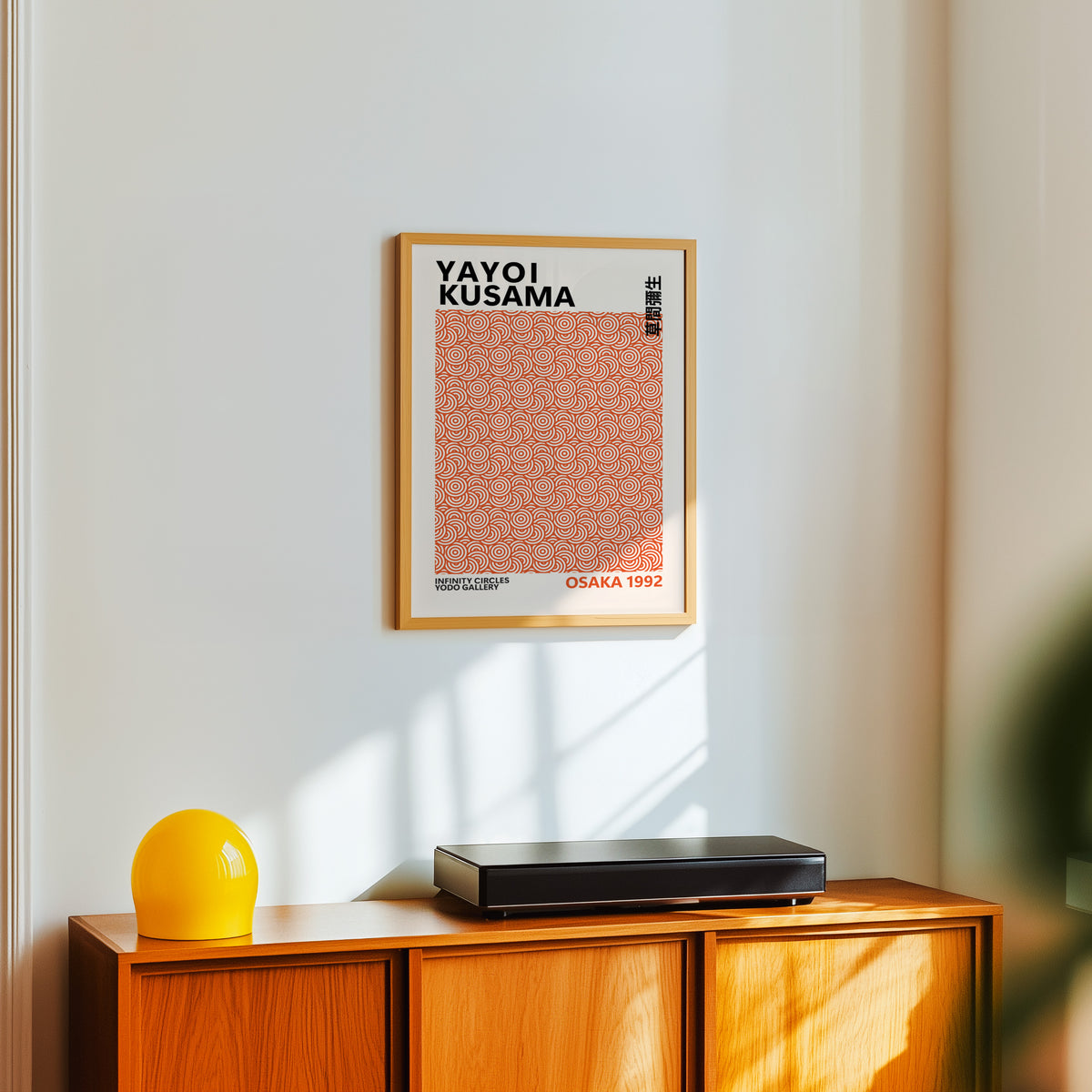 Yayoi Kusama inspired burnt orange circle print above a sideboard with a yellow lamp
