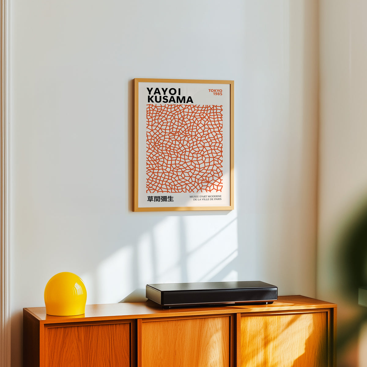 Yayoi Kusama inspired burnt orange net print above a sideboard with a yellow lamp