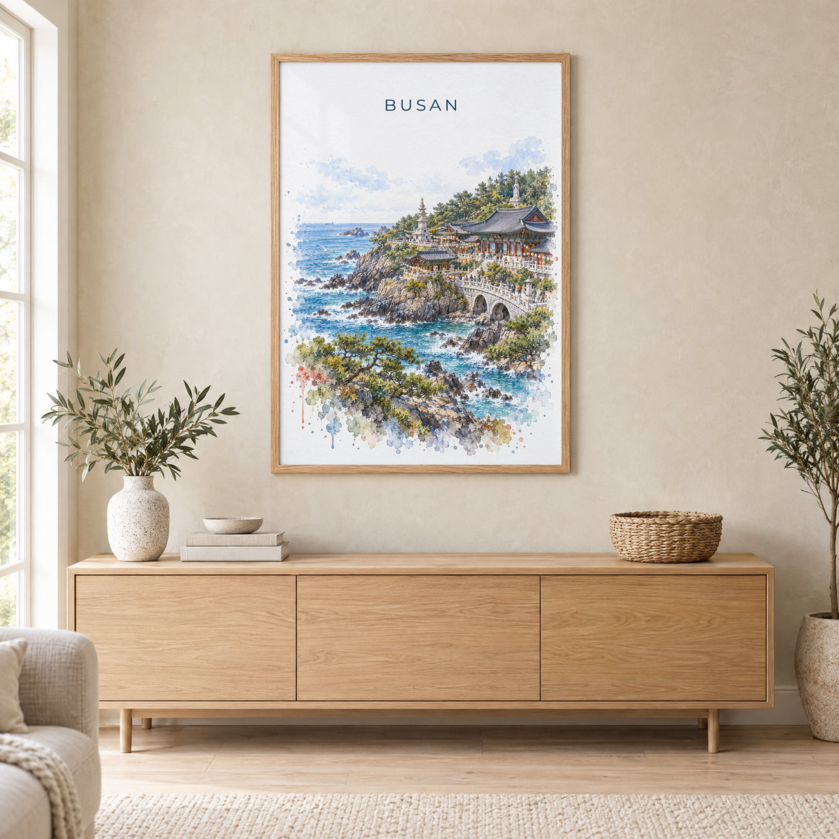Busan watercolor print in an oak frame above a light wood sideboard in a Scandinavian living room