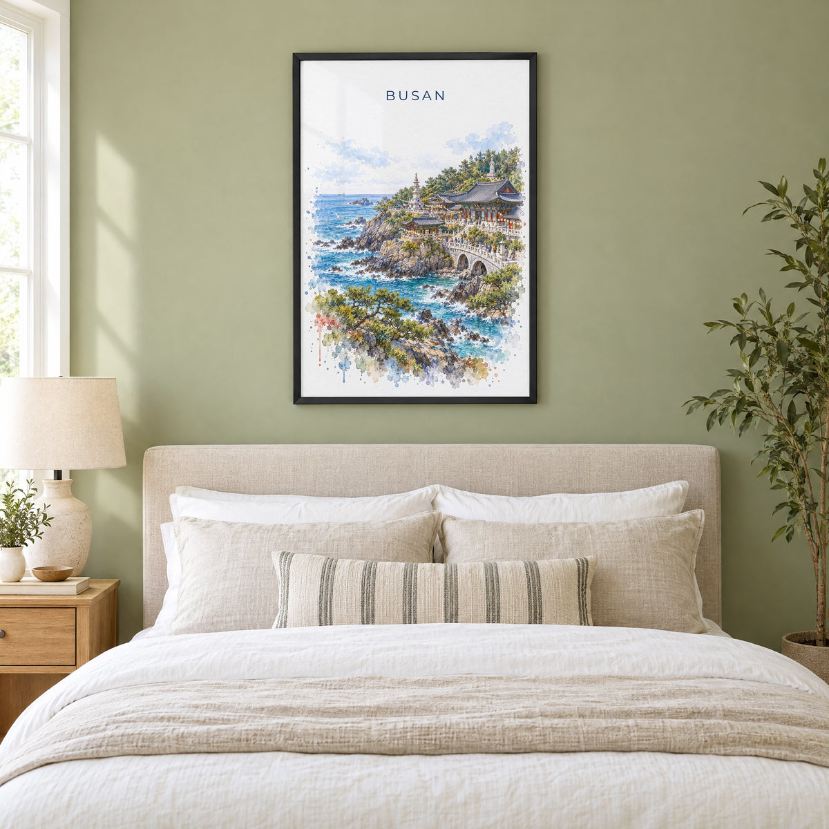Busan watercolor print in a black frame above an upholstered headboard in a sage green bedroom