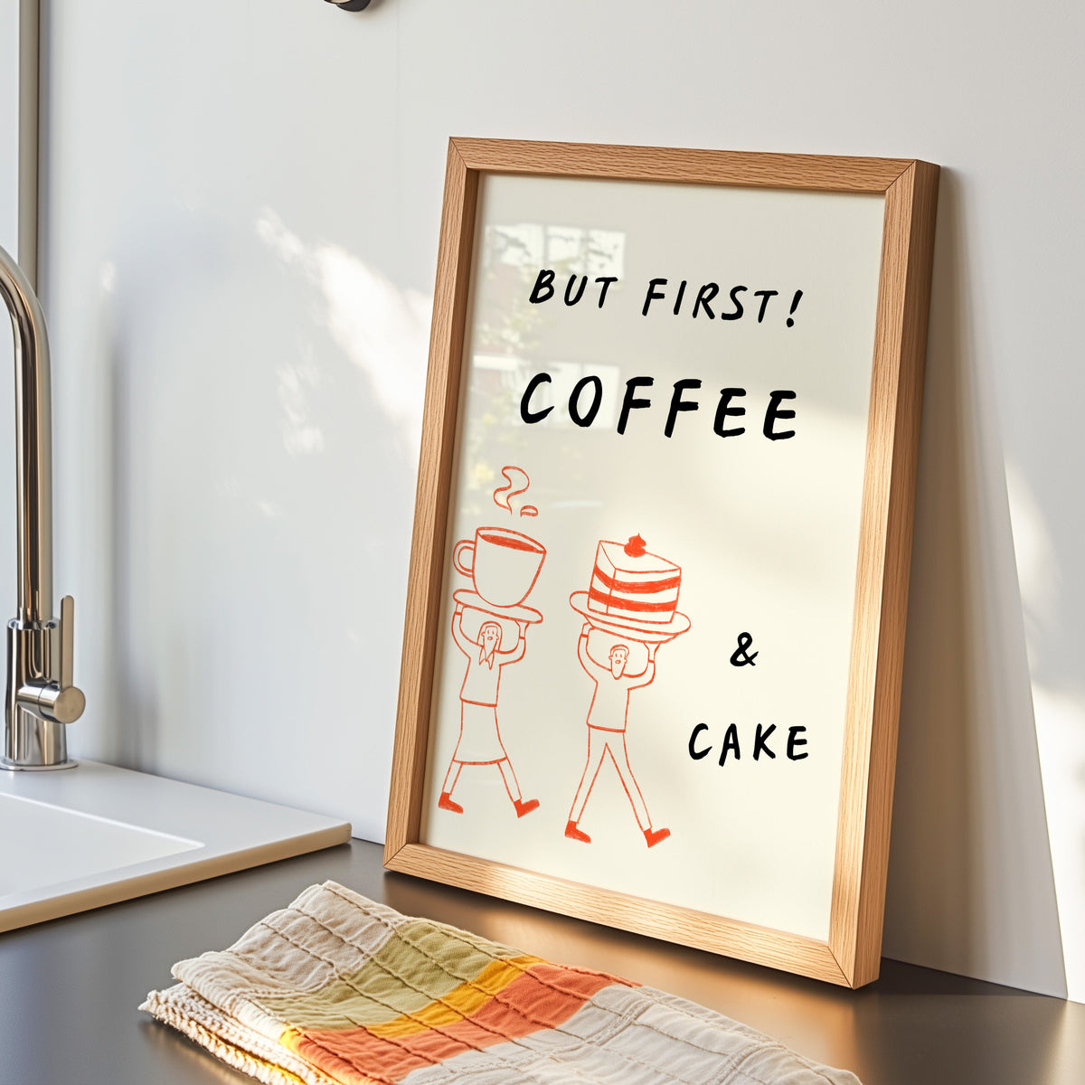 But First Coffee and Cake print in an oak frame by the kitchen sink beside a striped tea towel