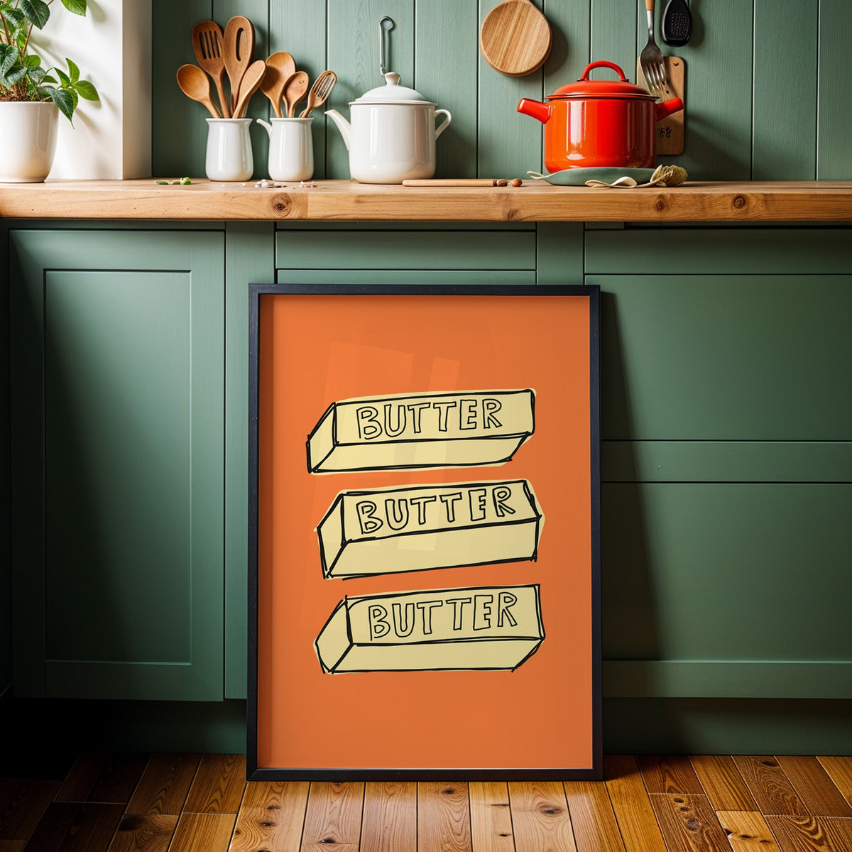 Butter blocks print in a black frame against sage green kitchen cabinets