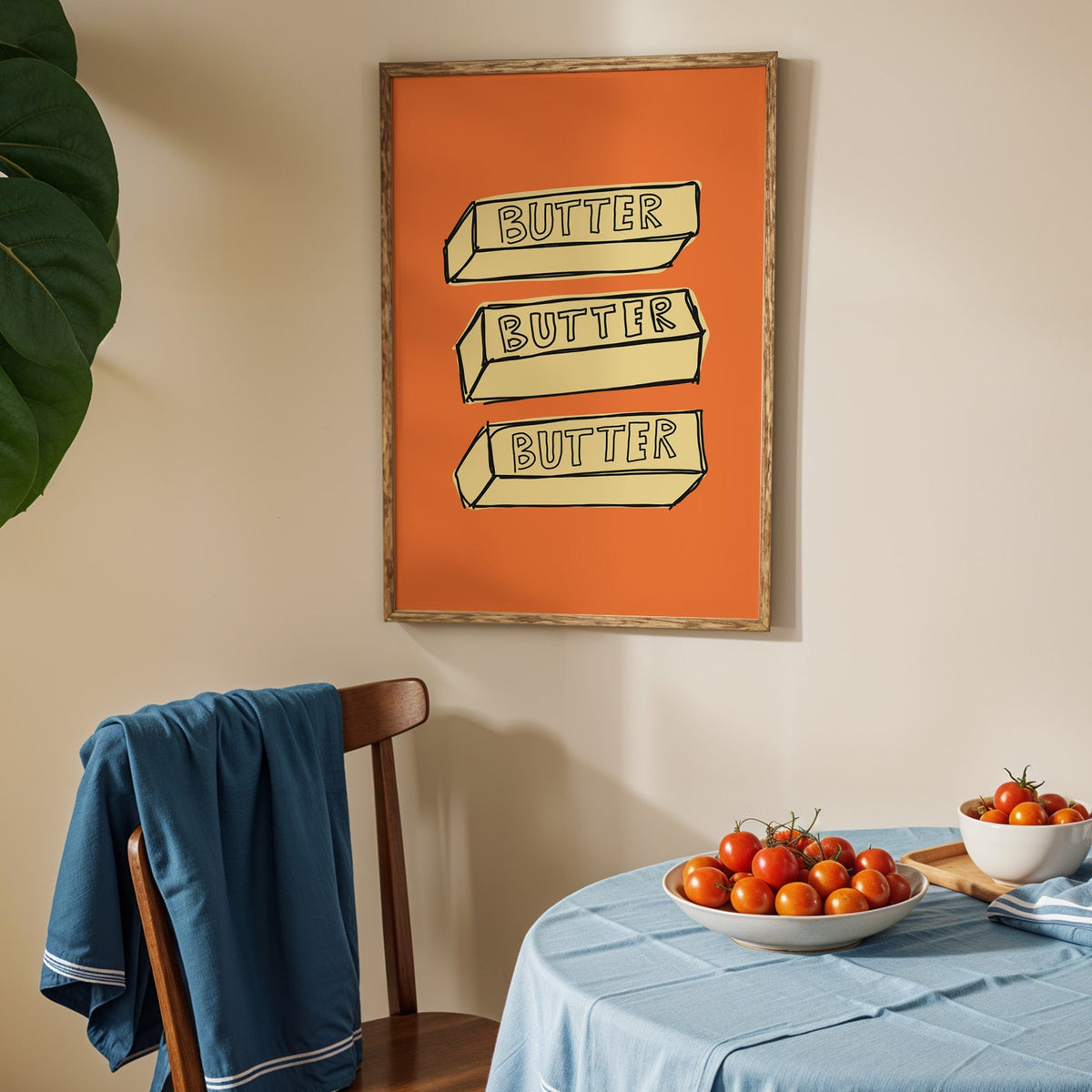 Butter blocks print in an oak frame above a blue linen table with ripe tomatoes