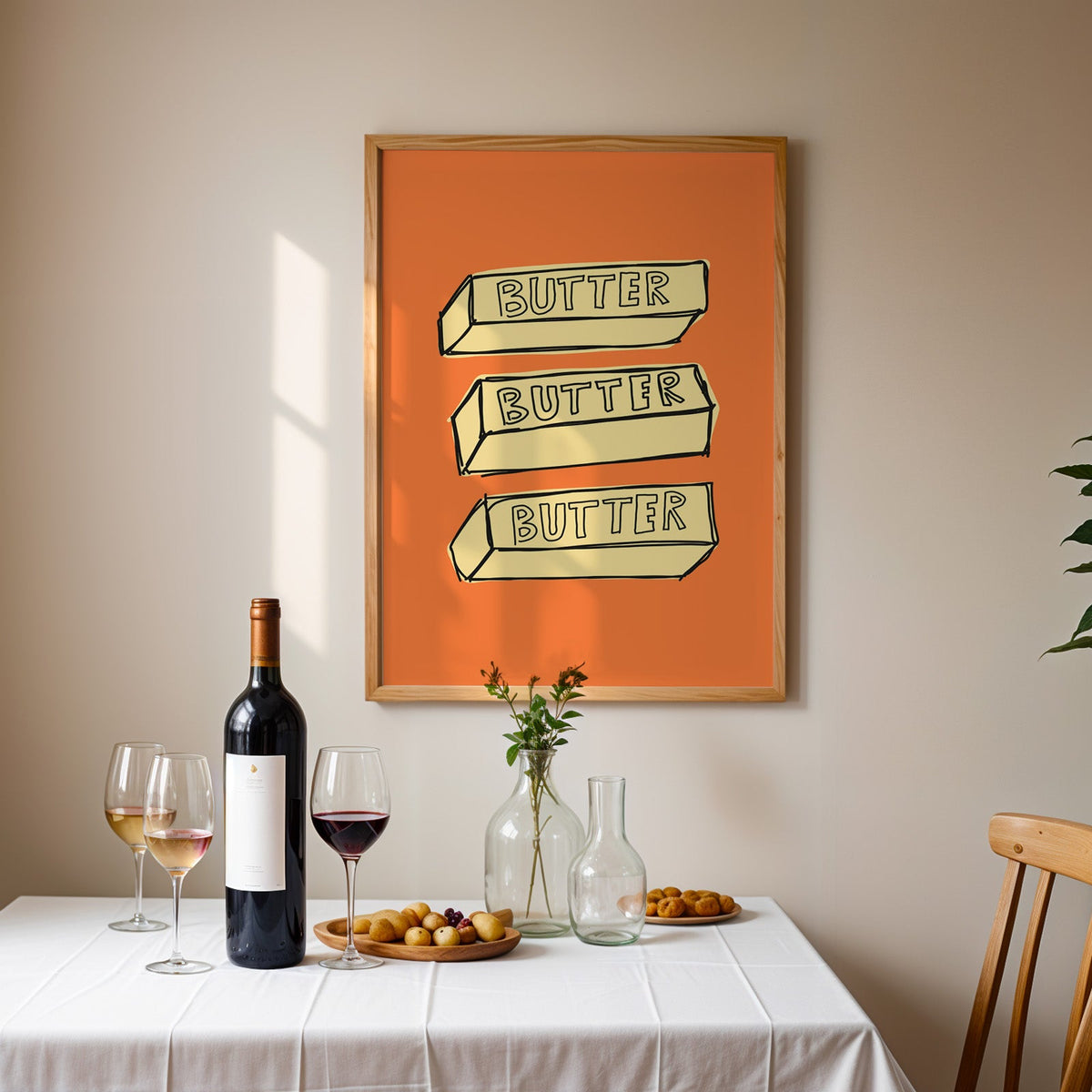 Butter blocks print in an oak frame above a table laid with red wine and glasses
