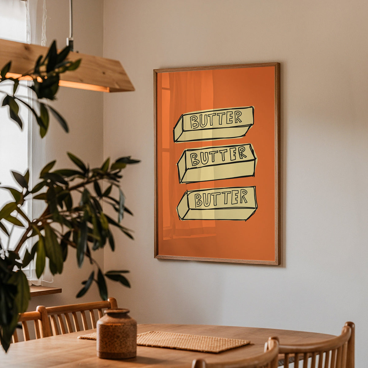 Butter blocks print in a walnut frame above a dining table beside an olive tree
