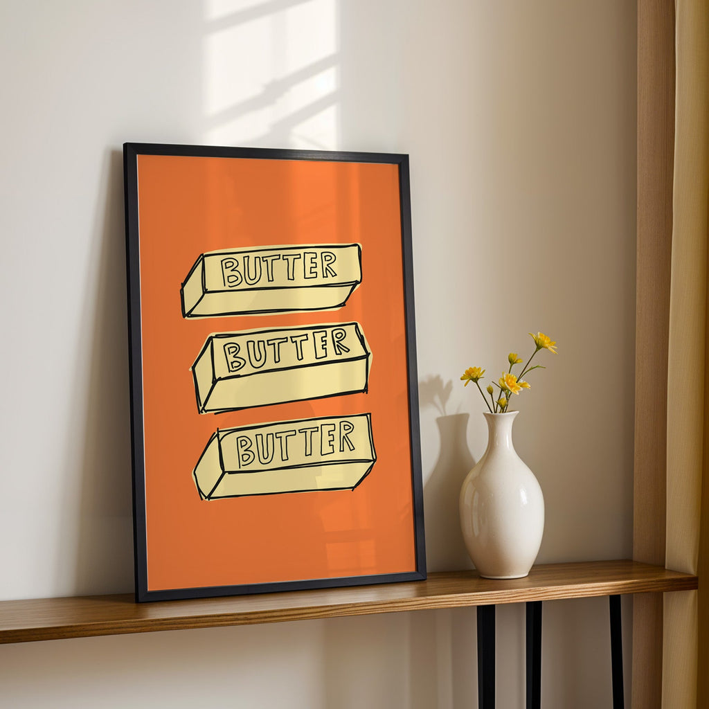 Butter blocks print in a black frame on a console table with yellow daisies