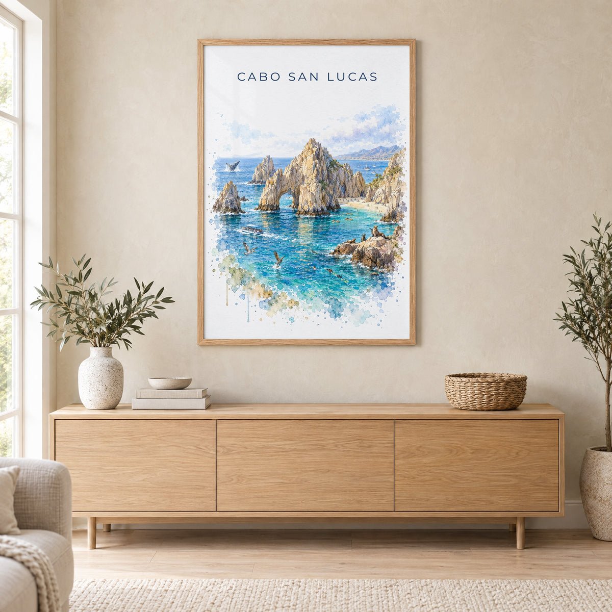 Cabo San Lucas watercolor print in an oak frame above a light wood sideboard in a Scandinavian living room