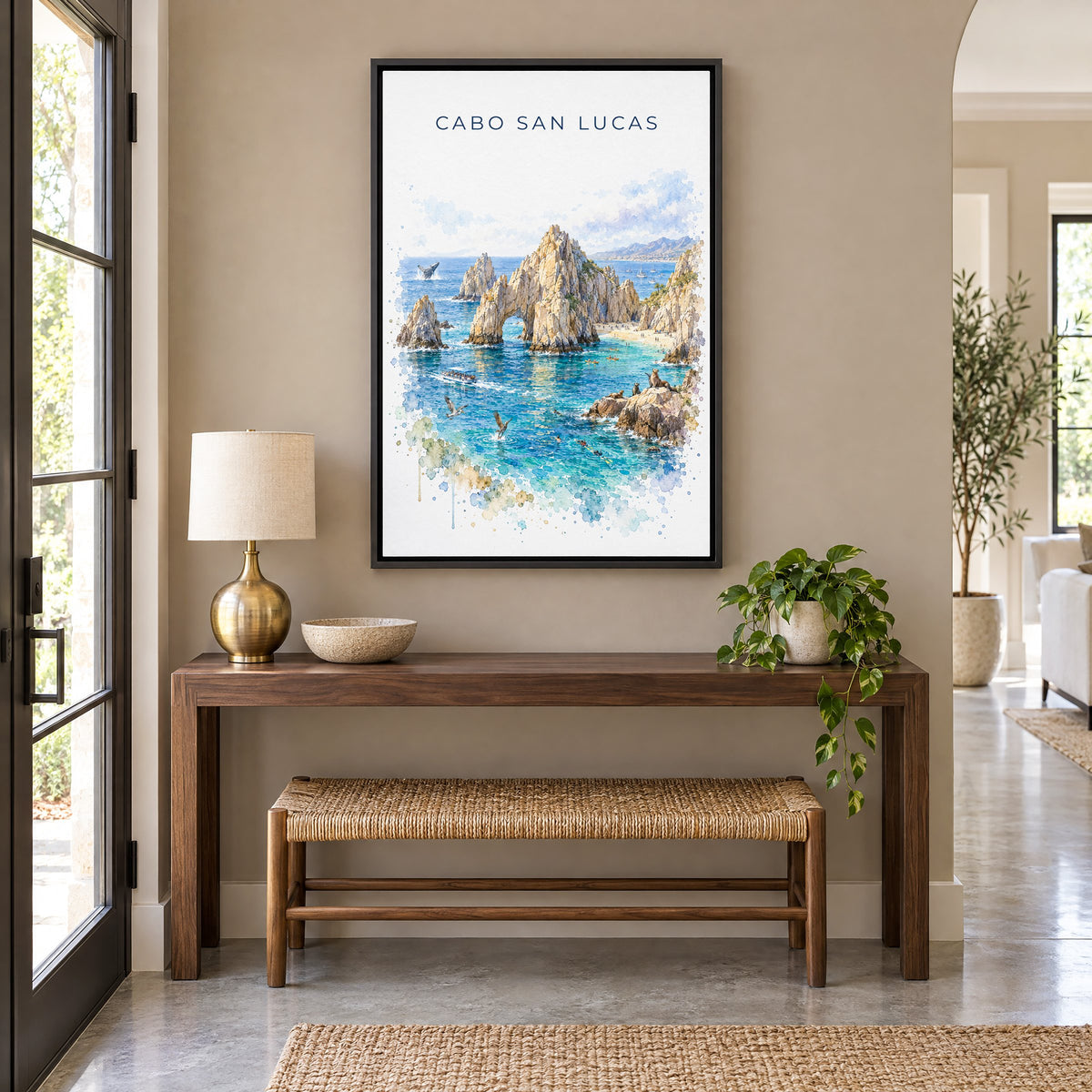 Cabo San Lucas watercolor print as a black floater canvas above a walnut console and woven bench in an entryway
