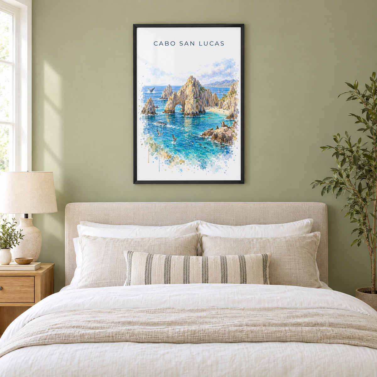 Cabo San Lucas watercolor print in a black frame above an upholstered headboard in a sage green bedroom